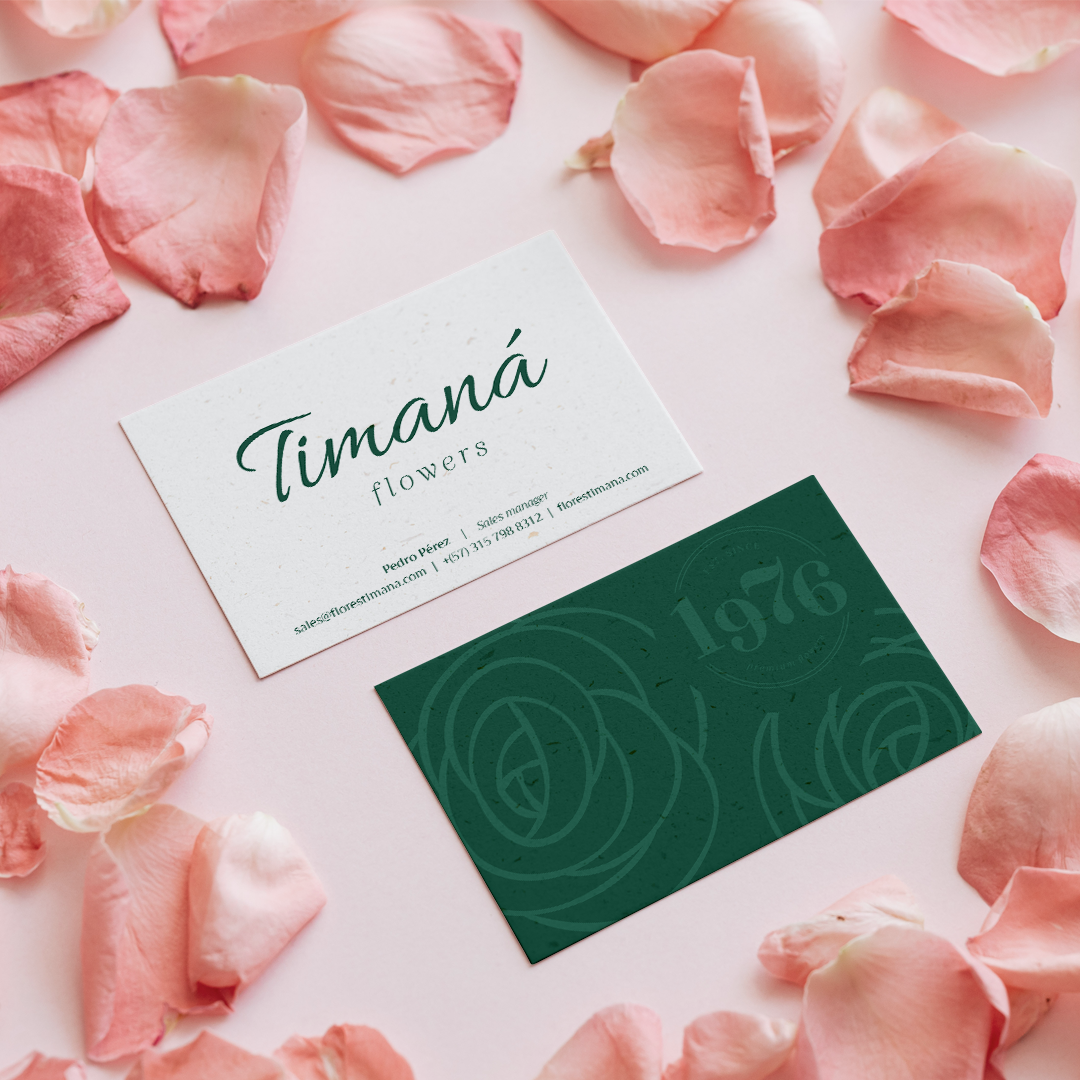 Timaná Flowers business cards — white front, forest green back, rose petals around