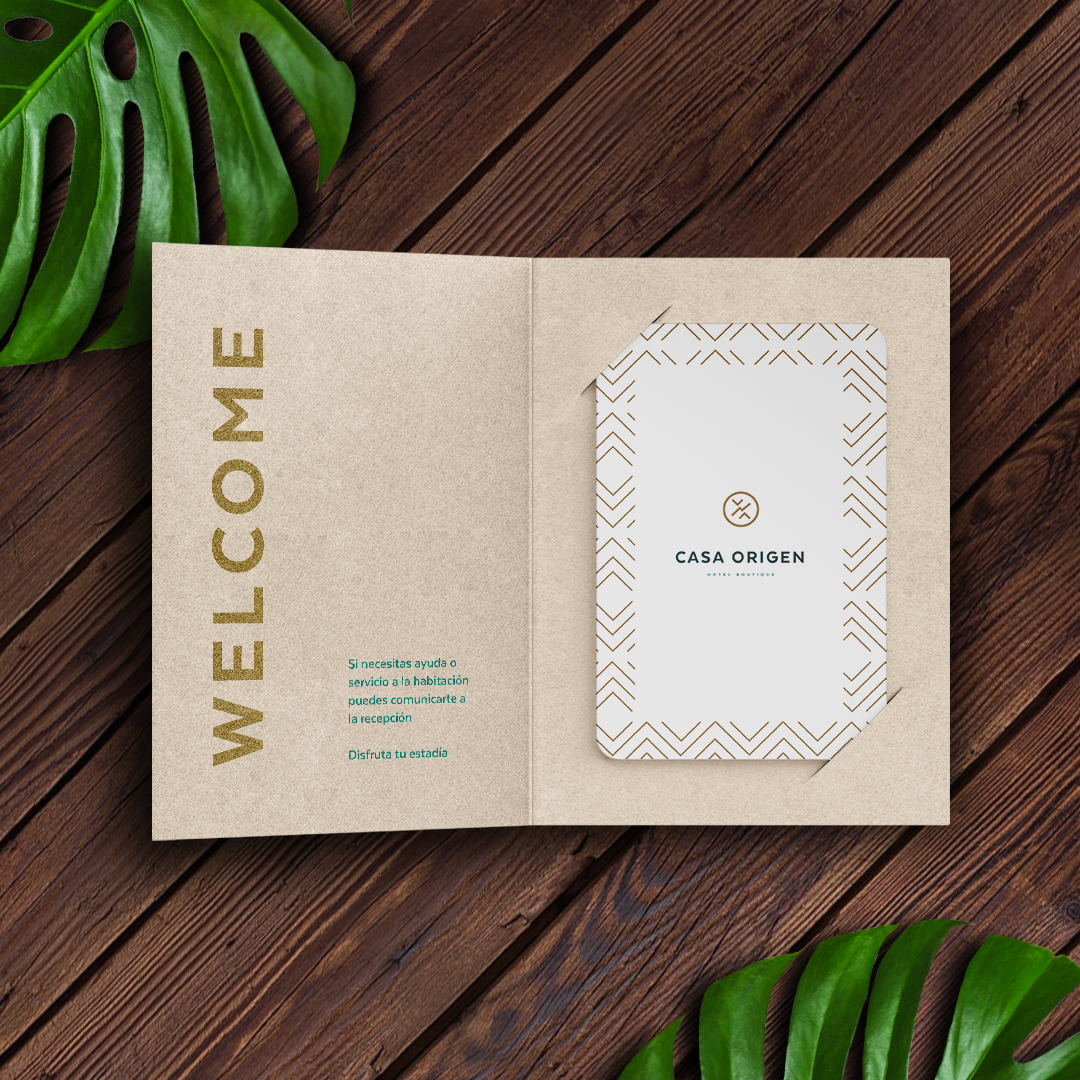 Casa Origen room key and welcome folder — kraft on dark wood with monstera leaves